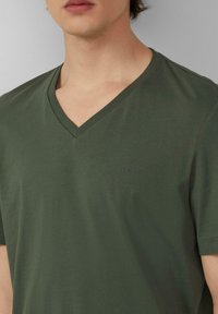 Olijfgroen v-hals t-shirt van zachte stof, met een klein geborduurd s.Oliver-logo op de borst, korte mouwen en een relaxte pasvorm.