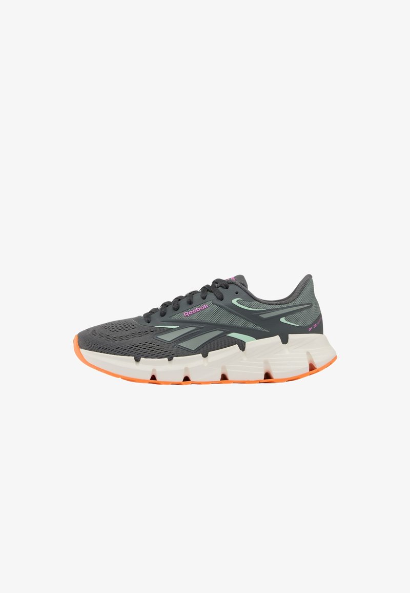 Chaussure de course Reebok gris foncé avec tige en mesh, accents vert clair, logo rose, semelle épaisse blanche avec crampons orange, et lacets noirs.