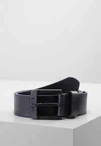 Ceinture en cuir bleu foncé avec une boucle en métal rectangulaire, logo en relief, texture lisse et design classique.