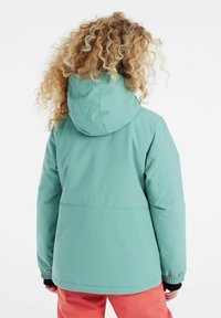 Veste à capuche bleu clair au toucher doux, avec des poignets élastiques et une coupe droite, associée à un pantalon corail vif. Coutures visibles et design de la capuche.