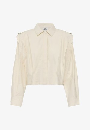 Cămașă croptată cu mâneci lungi, de culoare crem, cu guler ascuțit, nasturi frontali ascunși și detalii adunate pe umeri cu petite clame argintii.