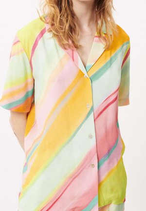 Personne portant une chemise à manches courtes boutonnée avec des rayures diagonales pastel en jaune, rose, vert, orange et bleu.