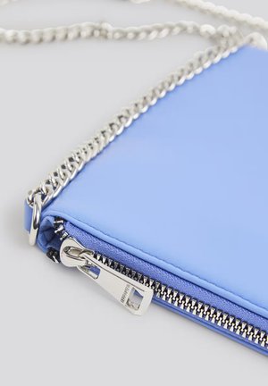Borsa a tracolla blu in pelle con una tracolla in catena argentata. Presenta una chiusura con zip e cuciture visibili. Texture liscia e forma rettangolare.
