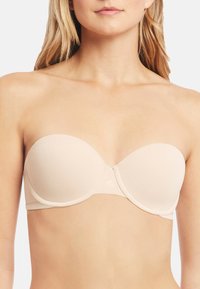 Beige strapless bra valmistettu sileästä kankaasta, jossa on muotoiltu malli ja alusvaatteen tuki, muotoillut kupit ja minimaalinen brändäys.