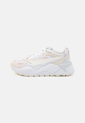 Zapatillas ligeras en blanco con acentos en beige y azul claro. Presentan una parte superior texturizada con superposiciones suaves y una suela gruesa y acolchada.