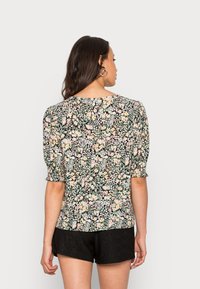 Blusa de estampado floral em preto, com mangas curtas e volumosas e um decote redondo, feita de um tecido leve com um acabamento texturizado.