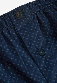 Navyblauwe stoffen shorts met een klein geometrisch patroon, voorzien van een elastische tailleband, een knoopsluiting en een ingenaaide merklabel.