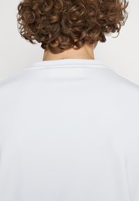 Weißes T-Shirt mit rundem Halsausschnitt und kurzen Ärmeln; glattes Baumwollmaterial mit leichter Textur; keine sichtbaren Muster oder Akzente.