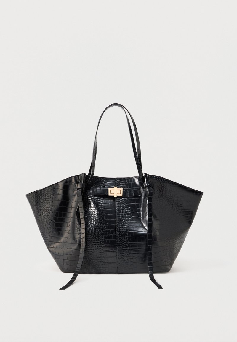 Sac fourre-tout noir avec texture crocodile, deux longues poignées et une petite fermeture rectangulaire dorée à l'avant.