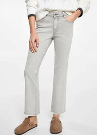 Sivé rozšírené džínsy s surovým lemom a prednými vreckami, vyrobené z denimu. V kombinácii s hnedými nazúvacími topánkami. Textúrovaný, stredne vysoký strih.