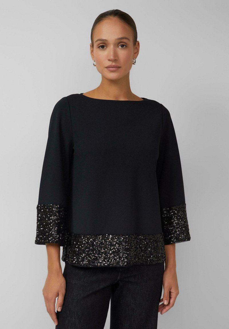Schwarzes Oberteil mit quadratischem Ausschnitt und dreiviertelärmel, mit einem schimmernden, mit Pailletten besetzten Saum und Bündchen für einen kontrastreichen Textur-Effekt.