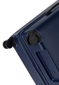 Valigia rigida blu navy con linee testurizzate, due ruote scorrevoli e una cerniera a scomparsa per una chiusura sicura.