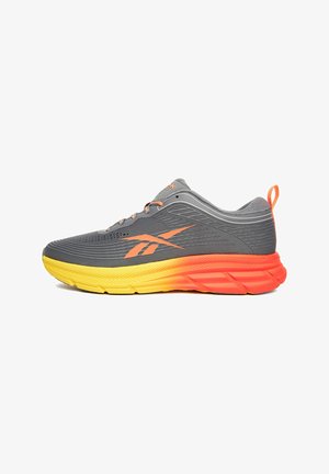 Grauer Sportschuh mit orange-gelbem Farbverlauf an der Sohle, atmungsaktivem Mesh-Obermaterial und kontrastierenden orangen Akzenten an den Schnürsenkeln und dem Logo.