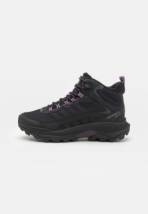 Black mid-height hiking boot with purple lace hooks, padded collar, textured sole, and "Merrell" branding on side, shown in profile.