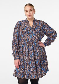 Pitkähihaisten mekko tummasta kankaasta, jossa on monivärinen abstrakti kuvio sinisen, beige ja punaisen sävyissä. Mekossa on napitettu etuosa ja kerätty vyötärö.