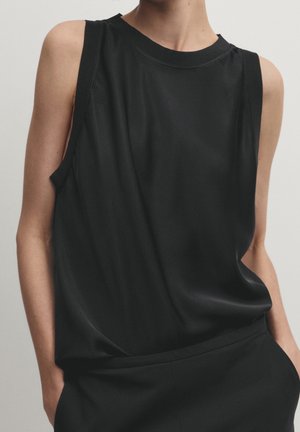 Black sleeveless top made of smooth fabric with a crew neckline and relaxed fit; features minimal seams and subtle side slits.
