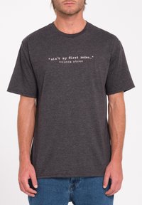 Mørkegrå bomulds t-shirt med korte ærmer, med hvid tekst: "ikke min første rodeo... volcom stone." Enkel crew neck design.