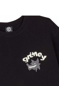 Czarny bawełniany t-shirt z białą i szaro grafika z napisem "grimey" oraz kreskówkowym wzorem potwora na lewej piersi.