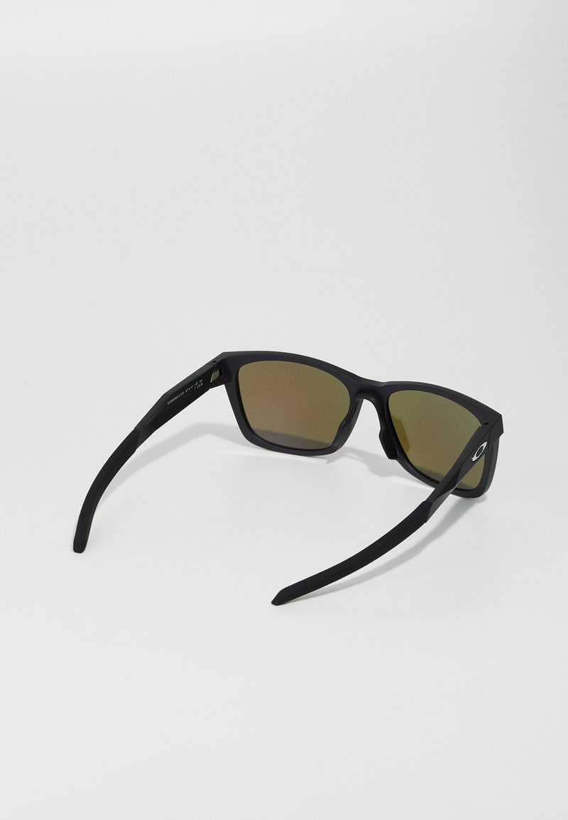 Occhiali da sole neri con lenti grigie, montatura rettangolare e aste spesse. Finitura in gomma testurizzata sulle tempie per una presa migliore.
