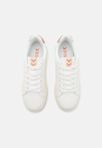 Paire de baskets blanches avec des lacets blancs et des logos Chevron orange sur la languette et la semelle intérieure, vues de dessus sur fond blanc.