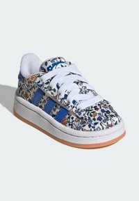 Textured white sneaker featuring colorful floral pattern, blue stripes, and white laces. Rubber sole with a tan accent at the bottom.