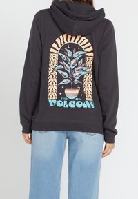Sweat à capuche noir ornant un graphique coloré d'une plante en pot avec des yeux, encadré par un arc décoratif et le texte "VOLCOM" en bas.