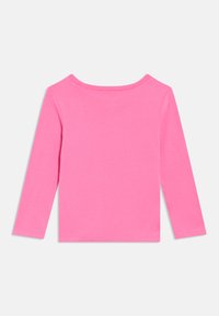 Gari piedurkņu spilgti rozā apaļas apkakles krekls, izlikts plakani, rādot aizmuguri uz balta fona.