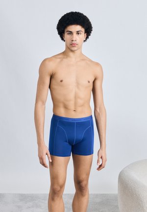 Boxer en coton bleu au design ajusté, avec une texture lisse et une taille élastique logo, présenté sur un mannequin.