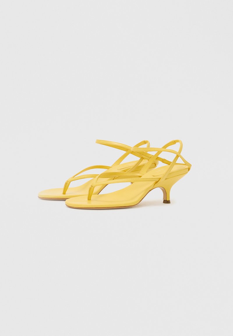 Yellow strappy sandals with a low, thin heel. Made of smooth material, featuring minimalist design and a toe post style.