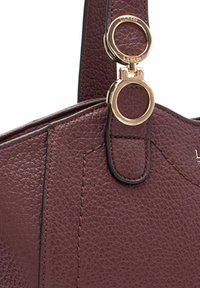 Borsa in pelle bordeaux con superficie texturizzata, dotata di accessori in oro e un dettaglio a forma di anello sul manico.