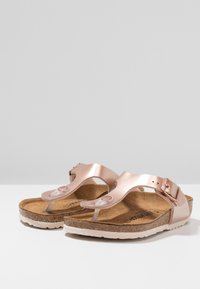 Sandali in pelle color oro rosa con parte superiore metallica, soletta in sughero e suola in gomma beige. Cinghia regolabile con un accento di fibbia in metallo.