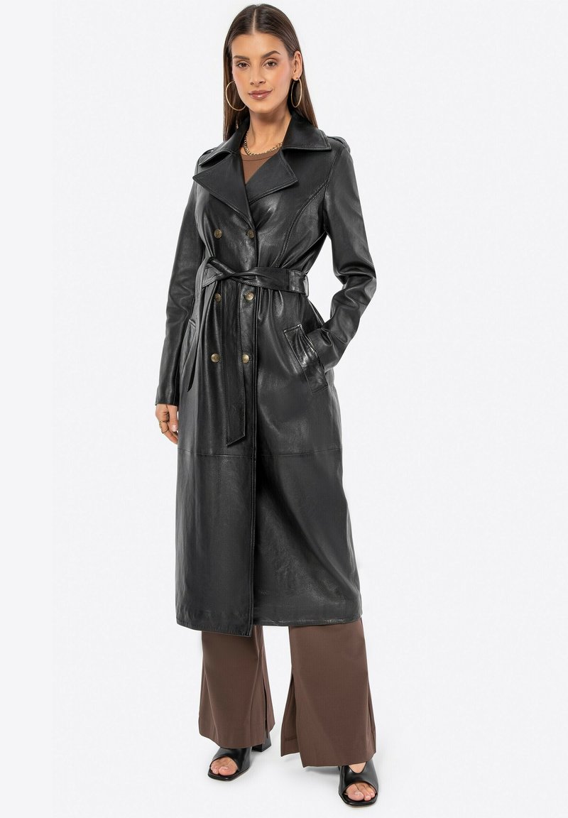 Trench coat de cuero negro con un frente de doble botonadura, gran cuello, cinturón en la cintura y bolsillos laterales; textura suave y longitud que alcanza la mitad de la pantorrilla.