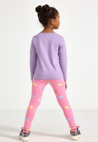 Μπλούζα μακρυμάνικη λεβαντί χρώματος σε συνδυασμό με ροζ κολάν με πολύχρωμα σχέδια καρδιών. Το ντύσιμο ολοκληρώνεται με αθλητικά παπούτσια με σχέδια.