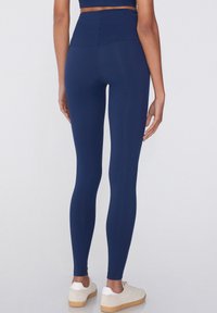 Leggings azul marino con cintura alta y un tejido suave y elástico. El diseño cuenta con una parte posterior sin costuras y un ajuste hasta el tobillo.