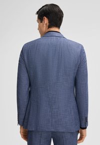 Blazer blu con texture, dalla vestibilità sartoriale, dotato di un singolo spacco, revers a punta e polsini con bottone. Vista posteriore mostrata.