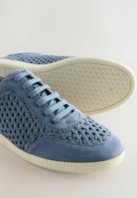 Plave suede tenisice s tkanom teksturom na stranama, okruglim vrhom i bijelim gumenim potplatima s geometrijskim uzorkom.