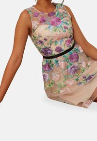 Vyšívané šaty s průsvitným béžovým překryvem, zdobené barevnými květinovými vzory v purpurové a zelené barvě, černý pás, bezrukávový design.