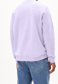 Lila sweatshirt med rund halsringning, ribbade muddar och fåll. Kombinerad med ljusblå jeans med klassisk femficksdesign.