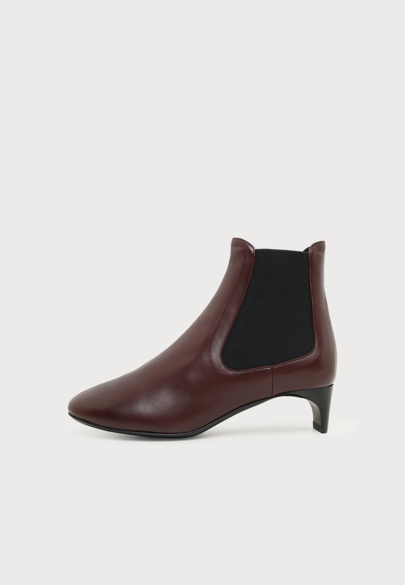 Bottine en cuir marron avec panneau latéral élastique noir et petit talon, vue de gauche sur fond blanc.