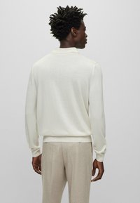 Helle beige Pullover mit Kragen, ausgestattet mit langen Ärmeln und einem lässigen Schnitt. Strukturierter Stoff mit geripptem Saum und Bündchen.