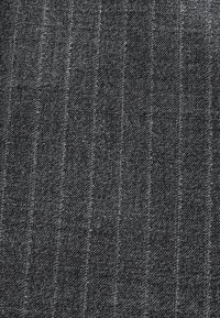 Tissu gris foncé avec de fines rayures verticales discrètes et un motif de tissage texturé.