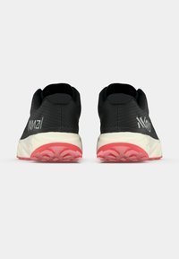 Baskets de course noires avec un dessus texturé, logo blanc et semelle extérieure corail contrastante. Col rembourré et conception de talon robuste pour le soutien.