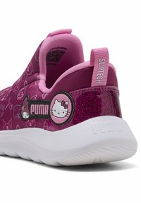 Vaaleanpunaiset liukuvat kengät, joissa on teksturoitu kangas ja Hello Kitty -kuviot sekä glitterinen korko. Valkoinen pohja, jossa on Puma-logo.