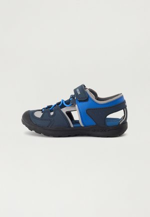 Sandale enfant bleu marine et bleu à bout fermé avec bride Velcro, côtés ouverts et semelle en caoutchouc pour activités en plein air.