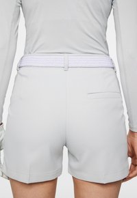 Grå shorts i slät väv, med ett flätat vitt bälte och en bakficka. Klippta ovanför knäet med rena fålldetaljer.