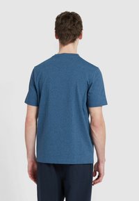 T-shirt a maniche corte in un tessuto blu melange, con collo rotondo e orlo dritto, indossato da una persona vista di spalle.