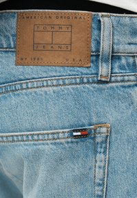 Φωτεινά γαλάζια τζιν από τζιν ύφασμα με καφέ δερμάτινο πατς με την επιγραφή Tommy Jeans και μικρό υφασμάτινο ετικέτα με τριχρωμία στην πίσω τσέπη.