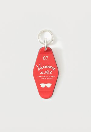 Etiqueta roja de llavero con anillo de metal, con la inscripción "07 Vacances de Kol, Riviera Francesa La Côte d'Azur" y un icono blanco de gafas de sol.
