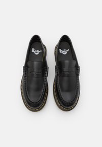 Sorte skinnloafere med en jevn overflate, med sydd tå og gule kontrastsømmer rundt sålen. Klassisk design og slip-on stil.