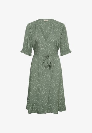Robe portefeuille verte à pois blancs, manches courtes bouffantes avec poignets à volants, ceinture à la taille et jupe évasée avec ourlet volanté.